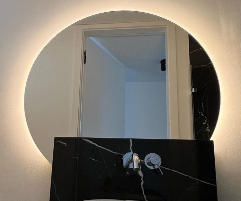 Runder Spiegel hinterleuchtet über einem modernen Waschbecken im Badezimmer